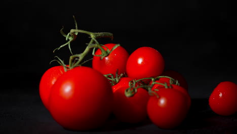 Close-up-of-a-tomato-falling-on-a-stack-of-tomatoes-in-slowmotion-with-a-black-background