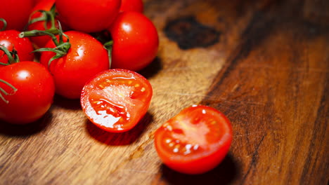 Handaufnahme-Einer-Männlichen-Hand,-Die-Auf-Einem-Holzschneidebrett-Eine-Rote-Tomate-In-Zwei-Hälften-Schneidet