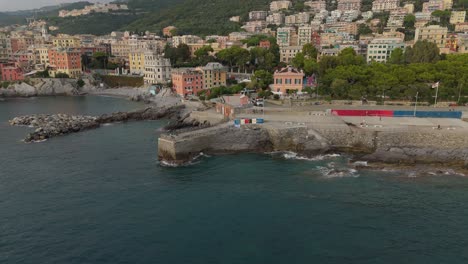 The-coastline-in-genoa,-italy-with-colorful-buildings-and-calm-sea,-daylight,-aerial-view