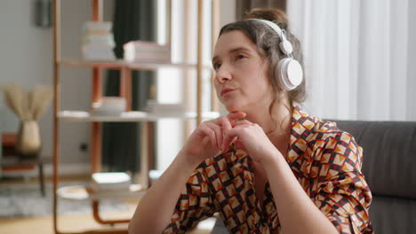 Woman-with-serious-facial-expression-wearing-headphones-in-living-room