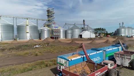 Grain-being-poured-into-a-truck-at-a-silo-complex-during-a-sunny-day,-agricultural-industry-scene