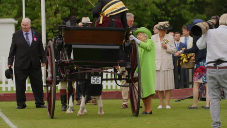 Queen-Elizabeth-in-a-green-dress-presents-trophy-to-carriage-driver-at-annual-show