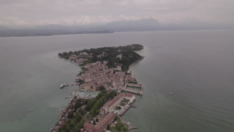 Drohnenaufnahme-Von-Simione,-Italien,-Mit-Blick-Auf-Die-Alte-Festung-An-Einem-Grauen-Tag-Mit-Booten-Im-Wasser-In-Der-Nähe-Des-Sees