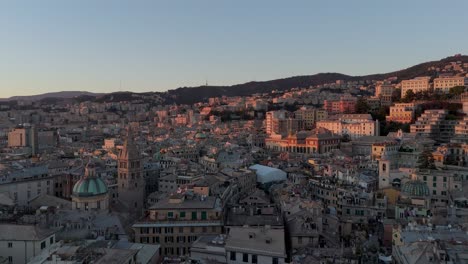 Golden-hour-view-of-Genoa's-historic-center-with-dense-buildings-and-hills-in-the-background,-aerial