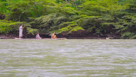 Menschen-In-Traditioneller-Kleidung-Navigieren-Durch-Einen-Fluss-In-Oxapampa,-Peru,-Mit-üppigem-Grün-Im-Hintergrund