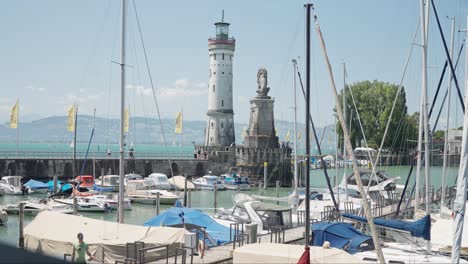 Sonniger-Tag-Im-Hafen-Von-Lindau-Mit-Angedockten-Booten-Und-Ikonischem-Leuchtturm-Und-Löwenstatue,-Klarer-Blauer-Himmel