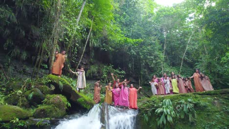 People-celebrating-traditional-ritual-in-Pucallpa,-Peru-by-waterfall,-lush-greenery,-daylight