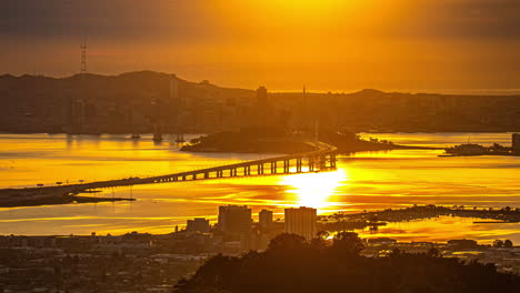 San-Francisco-Bay-Bridge-Und-Die-Skyline-Der-Stadt-Bei-Sonnenuntergang-–-Goldene-Wolkenlandschaft-Im-Zeitraffer,-Oakland,-Kalifornien