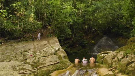 Person-leaping-into-a-pond-in-the-Oxapampa-jungle,-Peru,-surrounded-by-lush-greenery,-daylight