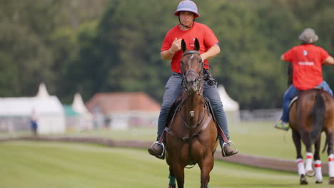 Polo-groom-in-red-shirt-canters-substitute-horse-up-the-green-field