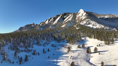 Morning-Aerial-Drone-sunrise-over-the-flatiron-Mountains-and-chautauqua-historic-park-in-Boulder,-Colorado-on-a-winter-morning-covered-with-snow