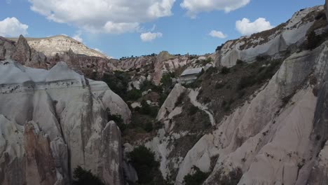 Approaching-drone-shot-going-through-the-natural-rock-formations-of-Cappadocia,-a-location-of-the-ancient-cave-houses-in-Turkey