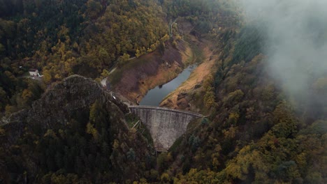 aerial-shot-of-gouffre-d'enfer-dam-near-Saint-Etienne,-loire-departement-on-a-foggy-day-with-low-clouds,-france