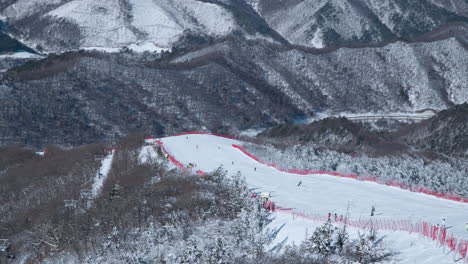 Esquiadores-Esquiando-Por-La-Colina-De-Las-Laderas-De-La-Montaña-Balwangsan-En-La-Estación-De-Esquí-De-Yong-Pyong-Pyeongchang-gun---Panorámica-Aérea-De-Alto-ángulo