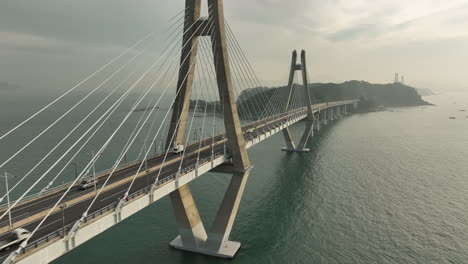 Aerial-view-of-bridge-to-Busan,-South-Korea-from-Geoje-Island-early-in-the-morning-as-traffic-passes-by