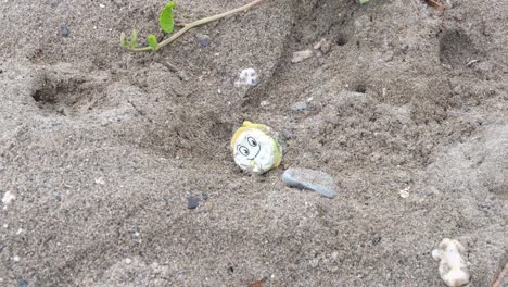 Discarded-plastic-toy-waste-with-a-happy-smiley-face-washed-onto-beach-from-ocean,-negative-environmental-and-marine-impact