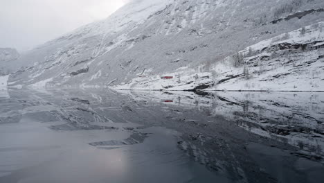 POV-footage-of-a-boat-ride-through-Geirangerfjord,-Norway,-highlighting-the-fjord's-tranquil-beauty-and-the-surrounding-snowy-mountains-in-winter