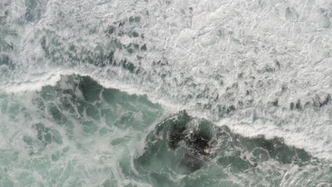 4K-overhead-of-different-ocean-surface-textures-as-waves-break-over-rocky-shoreline