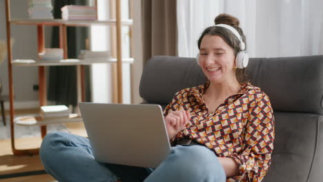 Relaxed-happy-woman-with-headphones-has-virtual-meeting-on-laptop