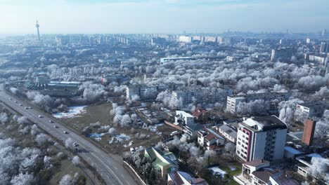 Aerial-View-of-Cars-Driving-Through-Road-Along-The-Buildings-With-Ice-covered-Trees-In-Winter-In-Galati-City,-Romania