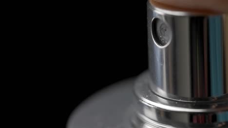Nahaufnahme-Einer-Silbernen-Sprühflasche,-Die-Nach-Unten-Gedrückt-Wird,-Um-Flüssigkeitsnebel-Vor-Schwarzem-Hintergrund-Auszustoßen