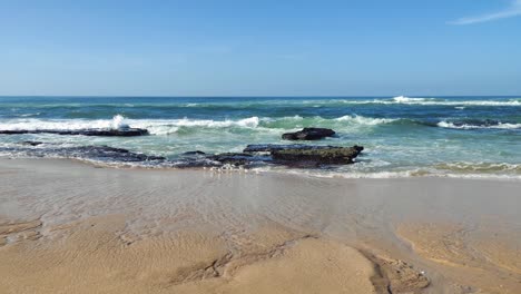 Ocean-waves-breaking-on-beach-shore,-seagull-running-from-sea-foam