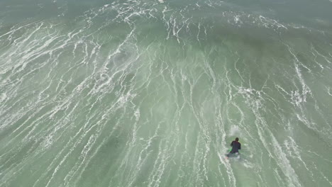 Surfer-dives-through-powerful-wave,-aerial-drone-view