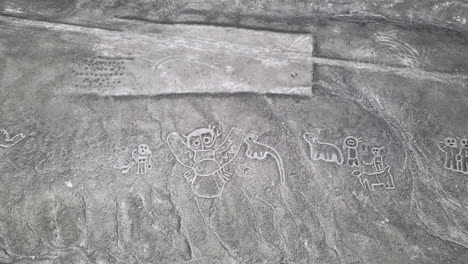 Top-down-aerial-above-humanoid-creatures-geoglyphs-in-the-Nazca-desert,-Peru