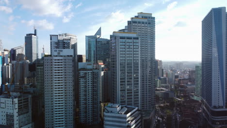Drone-circling-high-rise-apartments-in-Makati-city,-sunny-day-in-Manila,-Philippines
