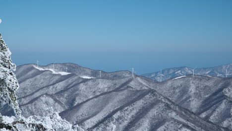 View-From-Monapark-Balwangsan-Mountain-on-Snowcapped-Daegwallyeong-Mountains-Valley-With-Huge-Wind-Turbine-Farm-on-Summits-on-Clear-Sky-Day-Pyeongchang-gun,-Gangwon-do,-South-Korea
