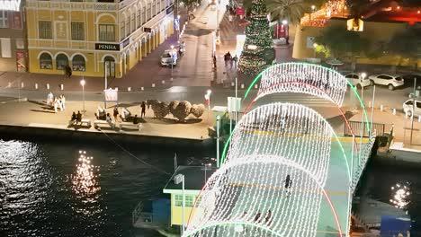 Aerial-tilt-up-as-lights-shimmer-reflecting-off-water-in-Willemstad-Curacao-at-night-during-Christmas