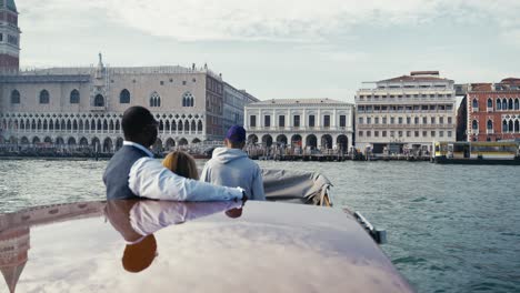 Mixed-race-couple-with-sunglasses-having-a-private-boat-ride-to-Palazzo-Ducale-and-Ponte-della-Paglia-in-Venice-italy-with-it-scenic-buildings