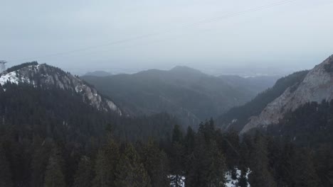 Wunderschöne-Panoramalandschaft-Mit-Bergen-Voller-Kiefern-Und-Schnee-Und-Einem-Nebligen-Himmel-Bei-Winterlichem-Schneefall