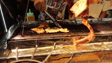 Hawker-flip-meat-of-skewered-crocodile-broiling-on-grill-at-street-food-market