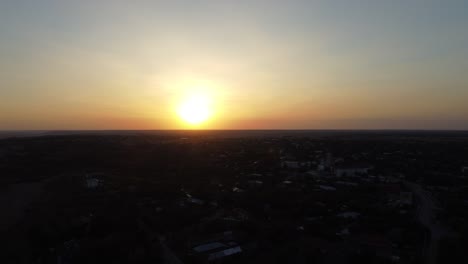 Luftaufnahme-Eines-Wunderschönen-Sonnenuntergangs-über-Einer-Stadt,-Die-In-Den-Schatten-Fällt