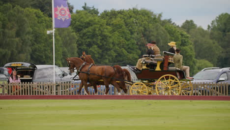 Carriage-with-gold-wheels-is-pulled-by-two-chestnut-horses,-four-people-ride-on-the-carriage