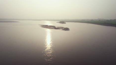 Verträumte-Luftaufnahme-Der-Sonnenlichtreflexion-Im-Schlammigen-Chenab-Fluss-In-Pakistan