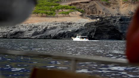Vista-Desde-Un-Barco-Navegando-En-El-Mar-Mirando-Otro-Barco-Y-Tierra-Con-Interés-Geológico,-Estilo-De-Vida-De-Viaje