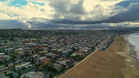 Iconic-Manhattan-beach-in-Los-Angeles-with-rainy-clouds-above,-aerial-view