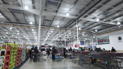 Wide-angle-shot-of-busy-Costco-checkout-lines-with-shoppers-and-employees,-fluorescent-lighting,-indoors