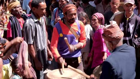 A-gathering-of-Timorese-people-at-a-traditional-cultural-welcome-ceremony-playing-the-drums,-singing-and-dancing-in-East-Timor,-Southeast-Asia