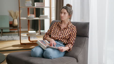 Woman-sits-in-modern-living-room-and-flips-through-coffee-table-book