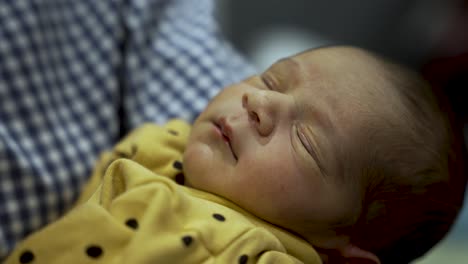 Newborn-baby-boy-sleeping-peacefully-in-a-yellow-outfit-with-polka-dots,-close-up