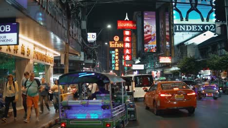 Tuk-Tuk-Taxifahrer-Bietet-Einer-Gruppe-Ausländischer-Touristen,-Die-Durch-Das-Pulsierende-Nachtleben-Im-Bangkoker-Chinatown-Viertel-Spazieren,-Eine-Fahrt-An