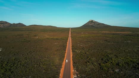 Luftaufnahme-Eines-Lieferwagens,-Der-An-Einem-Sonnigen-Tag-Auf-Einer-Geraden-Straße-Im-Cape-Legrand-Nationalpark-In-Westaustralien-Fährt,-Mit-Dem-Frenchman-Peak-Im-Hintergrund