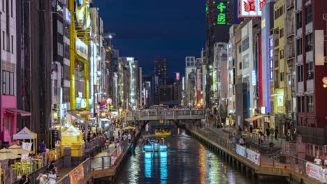 Lapso-Nocturno-De-Barcos-Pasando,-Personas-Y-Letreros-Iluminados-Vista-Desde-El-Puente-Ebisu-Canal-Dotonbori-Namba-Osaka,-Japón