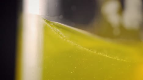 Seitenansicht-Mit-Geringer-Schärfentiefe-Einer-Gelben-Getränkeflüssigkeit,-Die-Sich-In-Zeitlupe-Im-Glas-Dreht