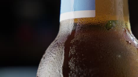 Nahaufnahme-Einer-Gekühlten-Bierflasche-Mit-Kondenswasser,-Dunkler-Hintergrund