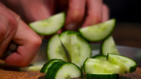 Close-up-of-a-male-hand-cutting-a-pre-cut-cucumber-into-multiple-pieces