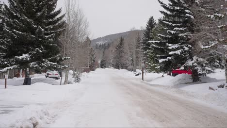 Zeitlupe,-Schneeflocken,-Die-Auf-Eine-Verschneite,-Vereiste-Straße-Fallen,-Kalte-Winterlandschaft-Und-Ein-Dorf-In-Colorado,-USA
